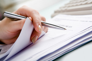 graphicstock close up of hand holding pen with paper over pile of documents HcgIXv6wEW thumb